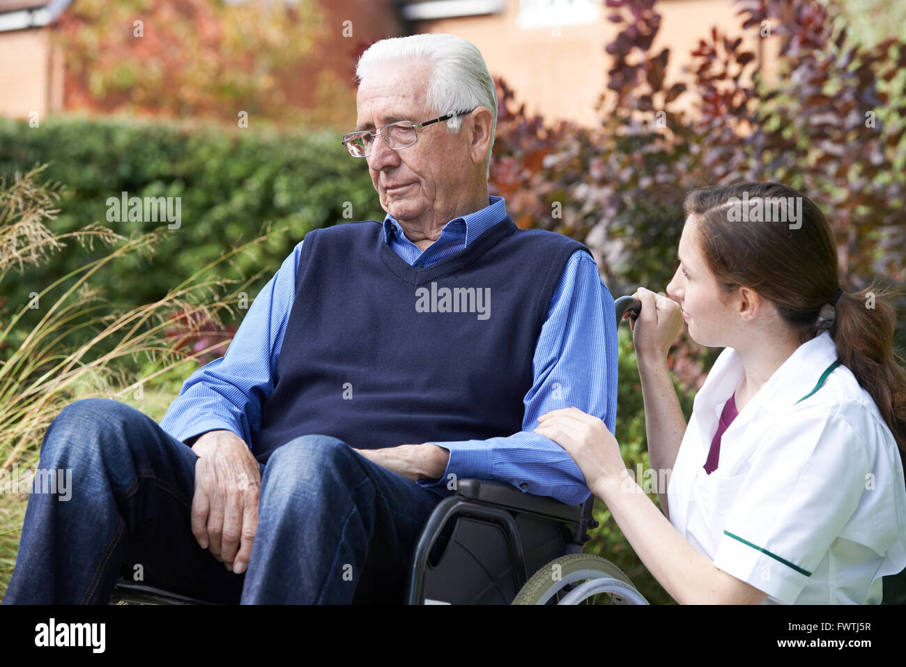 Nurse Comforting Senior Man In Wheelchair Stock Photo