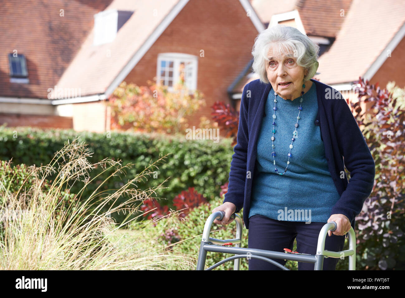 Senior Female In Garden Using Walking Frame Stock Photo - Alamy