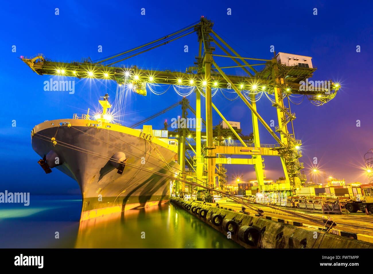 Industrial port with container ship at dusk Stock Photo - Alamy