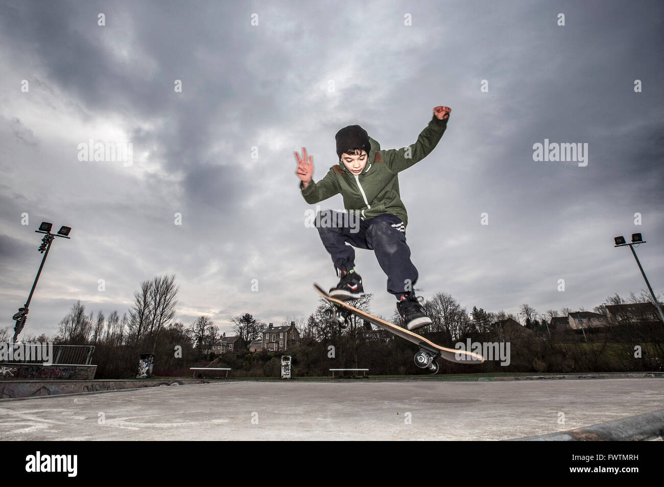 Boy skateboarding against stormy sky Stock Photo
