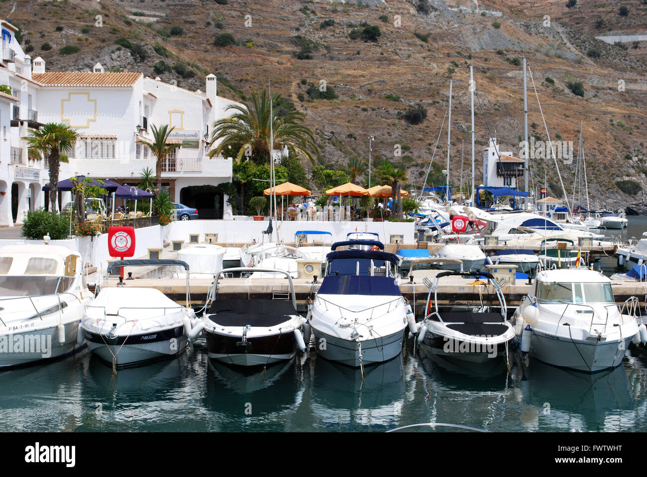 Yachts and boats moored in the marina with waterfront cafes to the rear, Marina del Este, Malaga Province, Andalusia, Spain. Stock Photo