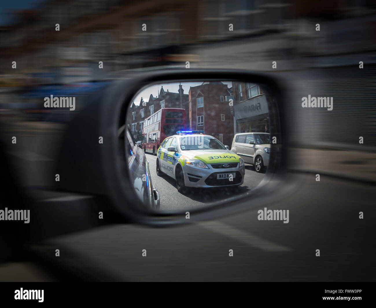 A police car chasing in a car's wing mirror Stock Photo
