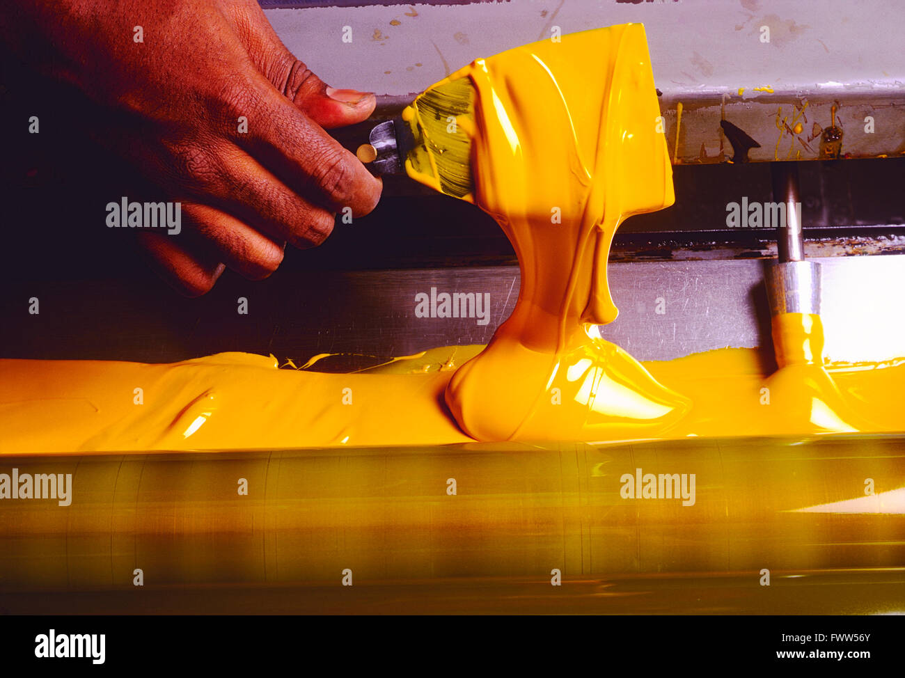 Close-up of African American printer's hand spreading printing ink with a blade hand tool Stock Photo