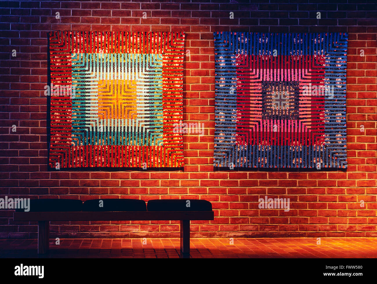 Decorative hand made quilts hang on brick wall in office space Stock Photo