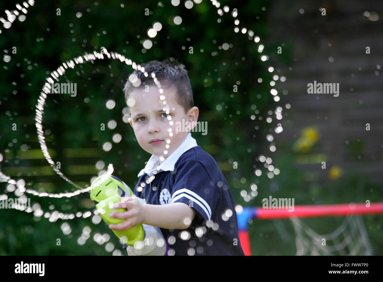 Boy playing in garden with water pistol Stock Photo