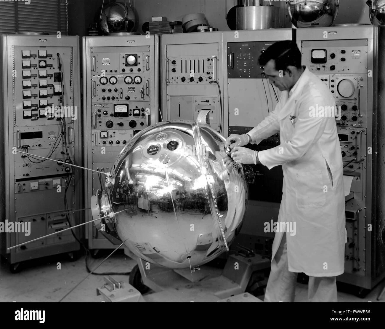 A NASA scientist makes adjustments to the Explorer XVII satellite probe at the Goddard Space Flight Center January 1, 1963 in Greenbelt, Maryland. The 405 pound pressurized stainless steel sphere measured the density, composition, pressure and temperature of Earth's atmosphere after its launch from Cape Canaveral on April 3, 1963. Stock Photo