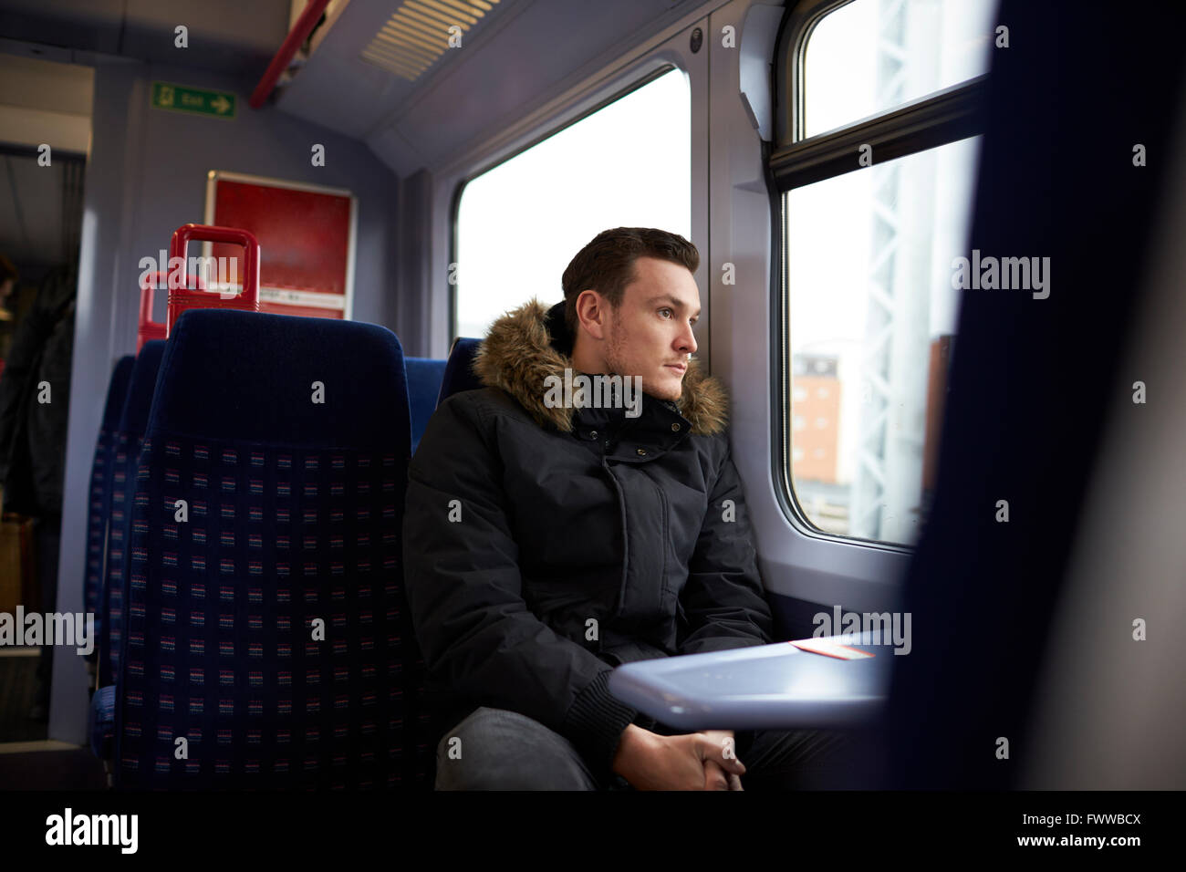 Young Man Sitting In Train Carriage On Railway Journey Stock Photo
