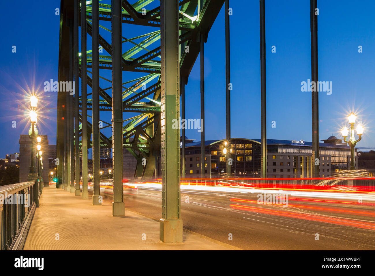 Car light trails as traffic crosses the famous Tyne Bridge in Newcastle upon Tyne, England, UK. Hilton Hotel in distance Stock Photo
