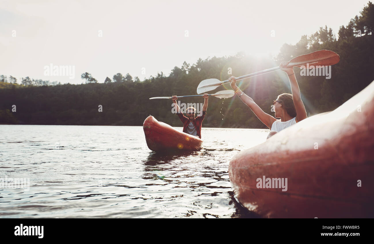 Happy young couple enjoying canoeing on summer day. Young man and woman having fun during kayaking. Stock Photo