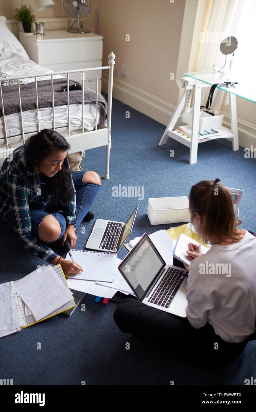 Two Female Students With Laptops Studying In Bedroom Stock Photo