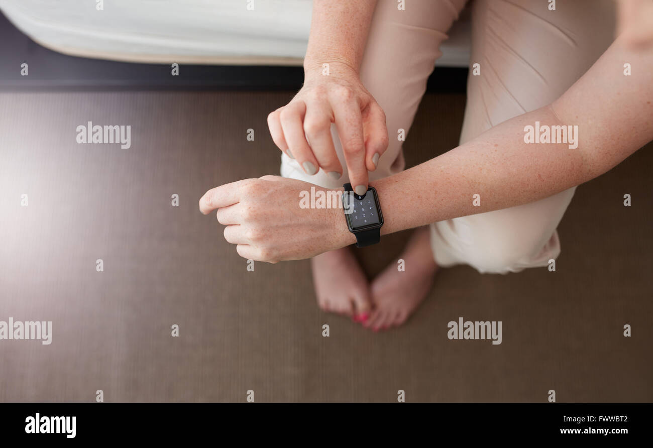 Overhead shot of female hands using smartwatch. Close up image of woman using smart wrist watch in bedroom at home. Dialing a ph Stock Photo