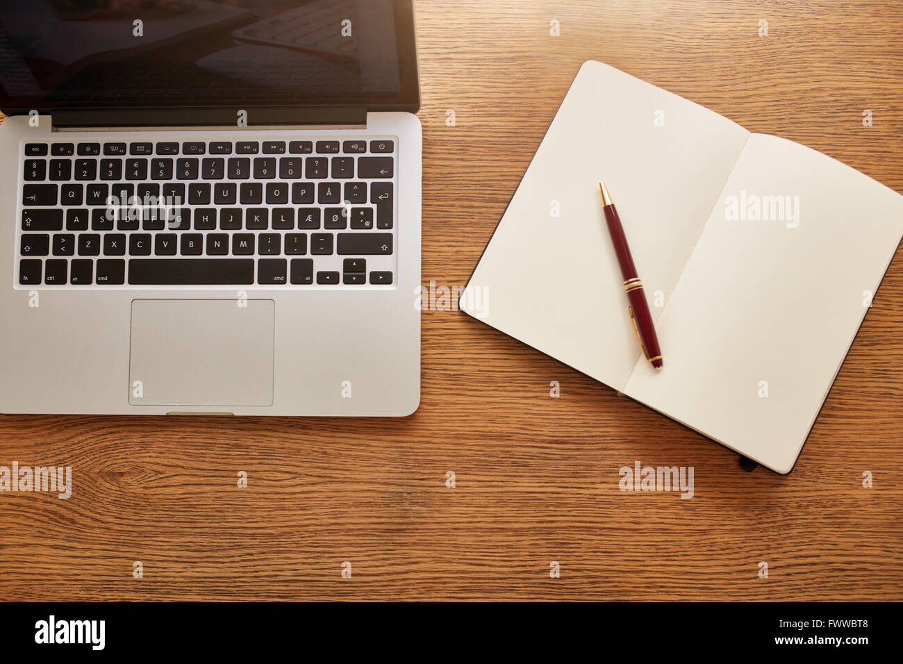 Top view shot of a laptop with diary and pen and on wooden table. Overhead view of working desk. Stock Photo