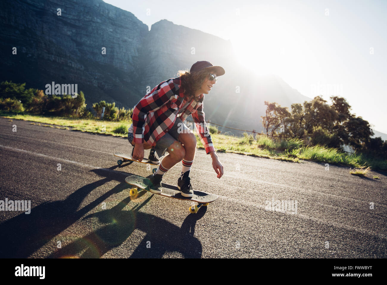 Young man longboarding outdoors on countryside road. Male skateboarding on a sunny day. Stock Photo