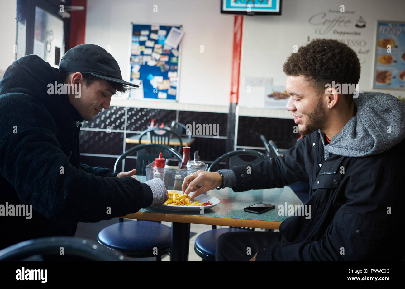 Two Male Students Eating Meal In Café Stock Photo