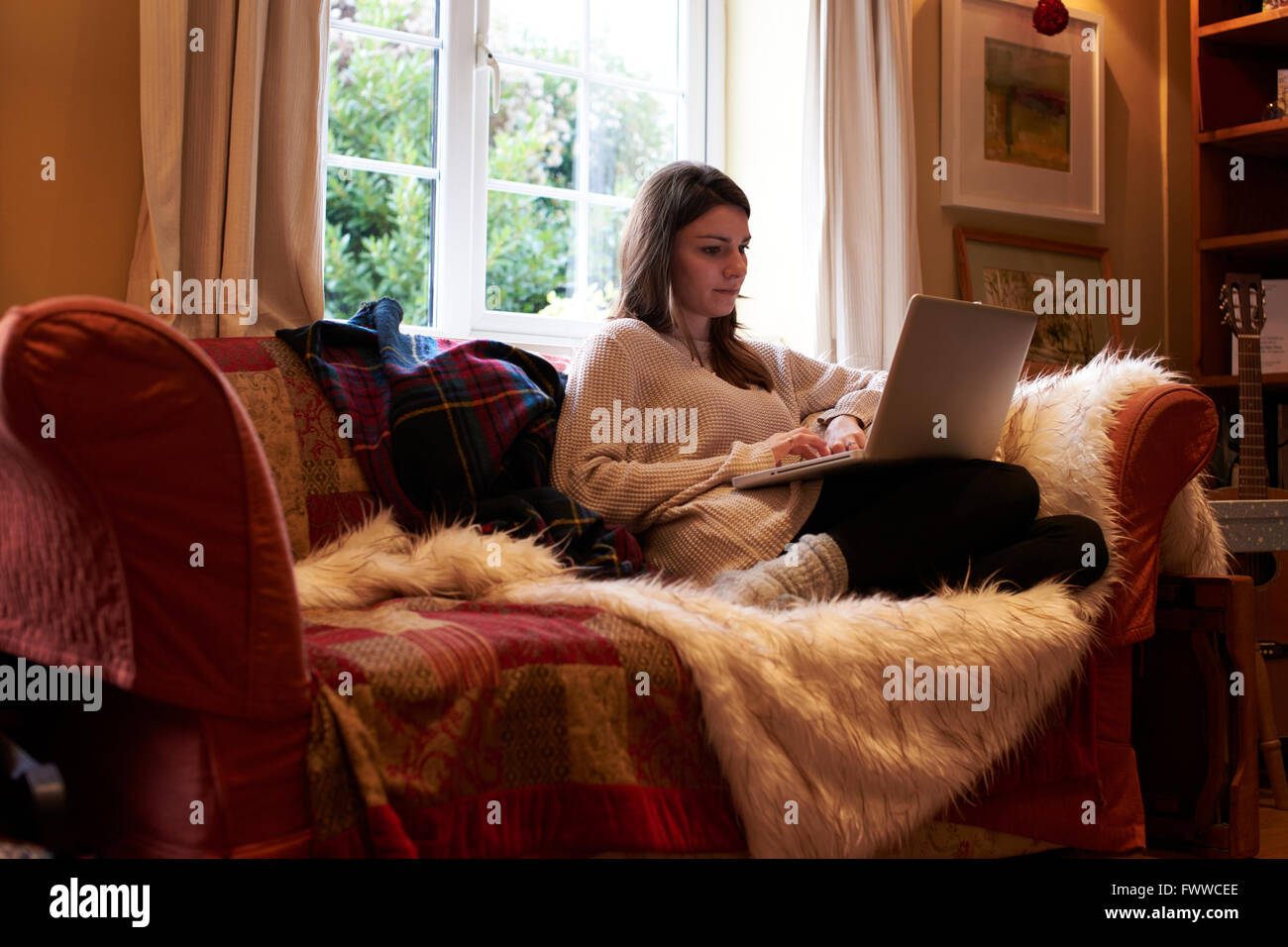 Young Woman At Home Sitting On Sofa Using Laptop Stock Photo - Alamy