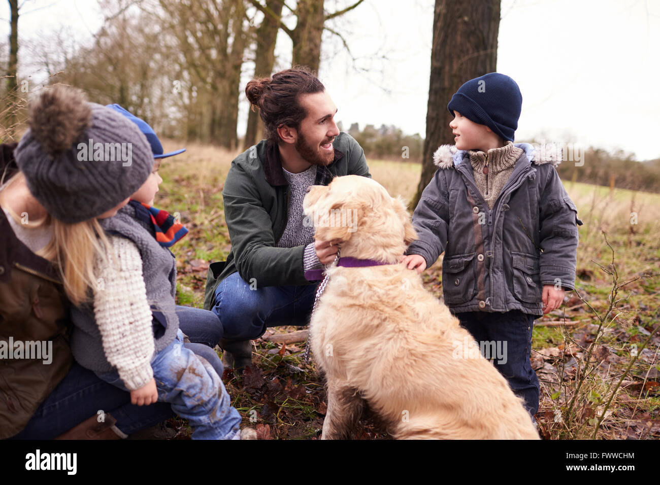 Family With Dog On Winter Walk Playing In Countryside Stock Photo