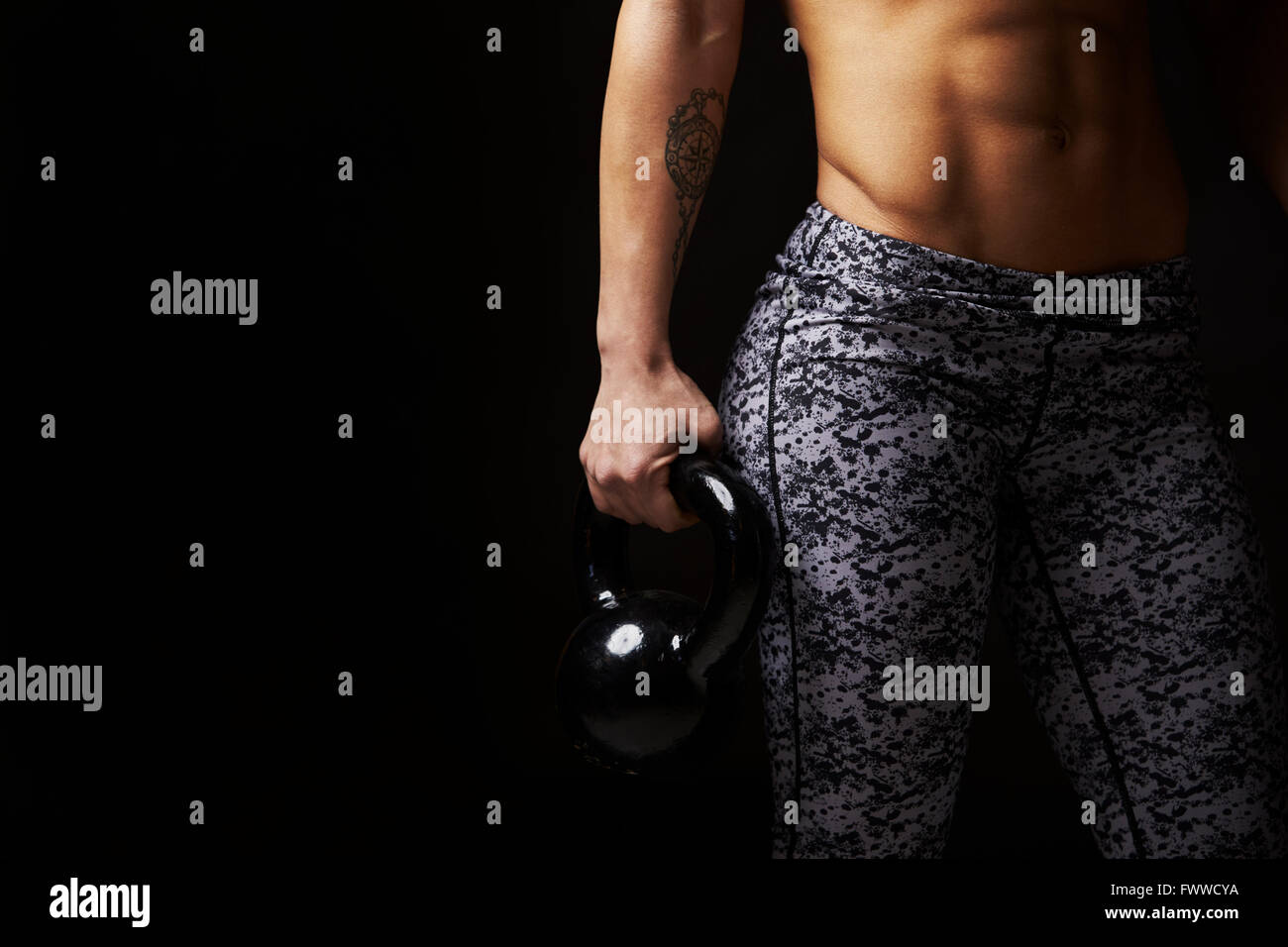 Mid-section crop of muscular young woman holding kettlebell Stock Photo
