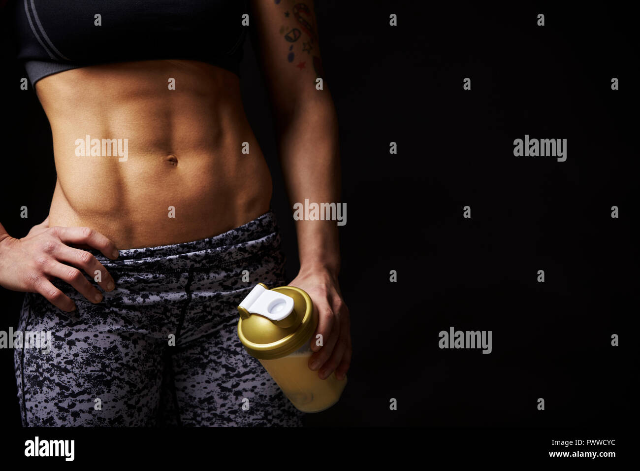 Mid-section crop of muscular young woman holding drink cup Stock Photo