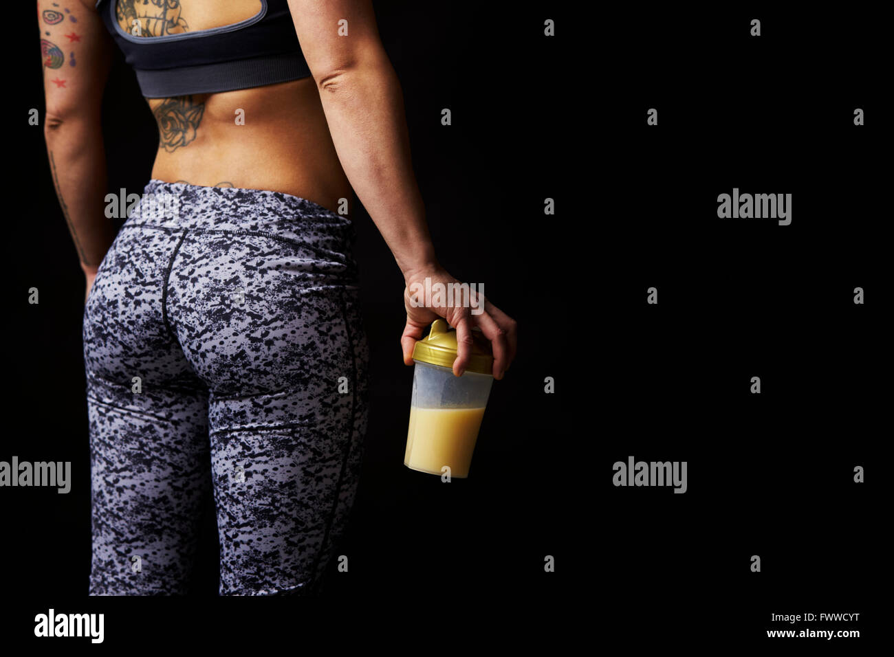 Mid-section of muscular young woman holding drink, back view Stock Photo