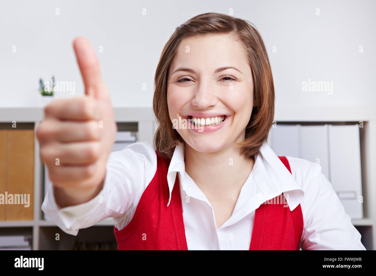 Happy business woman in her office holding thumbs up Stock Photo - Alamy