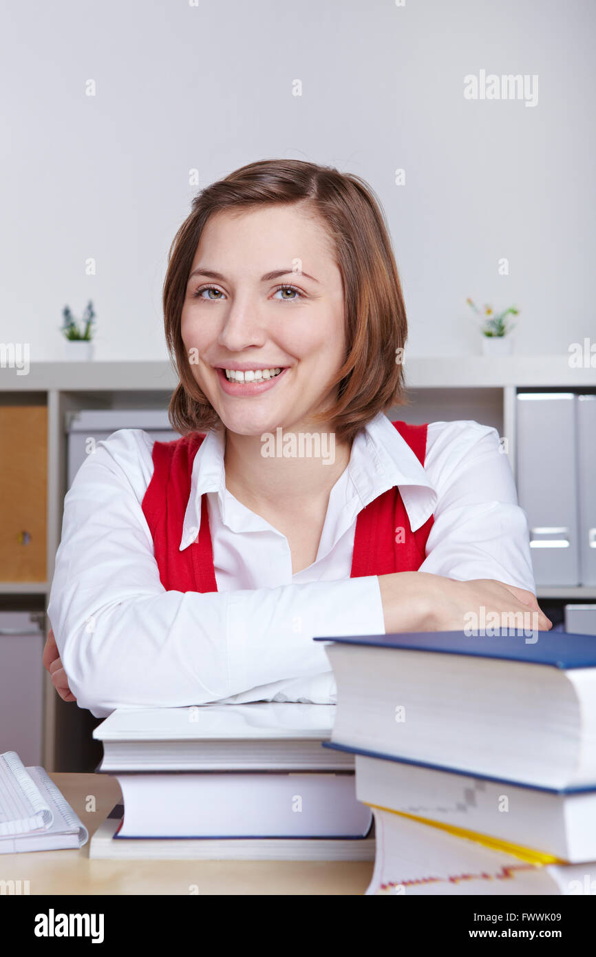 Portrait of happy smiling student with many books at her desk Stock ...