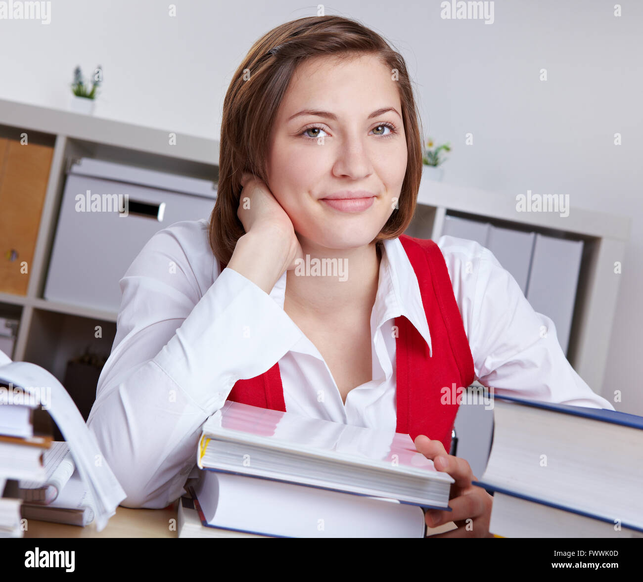 Smiling attractive woman learning at her desk with books Stock Photo ...