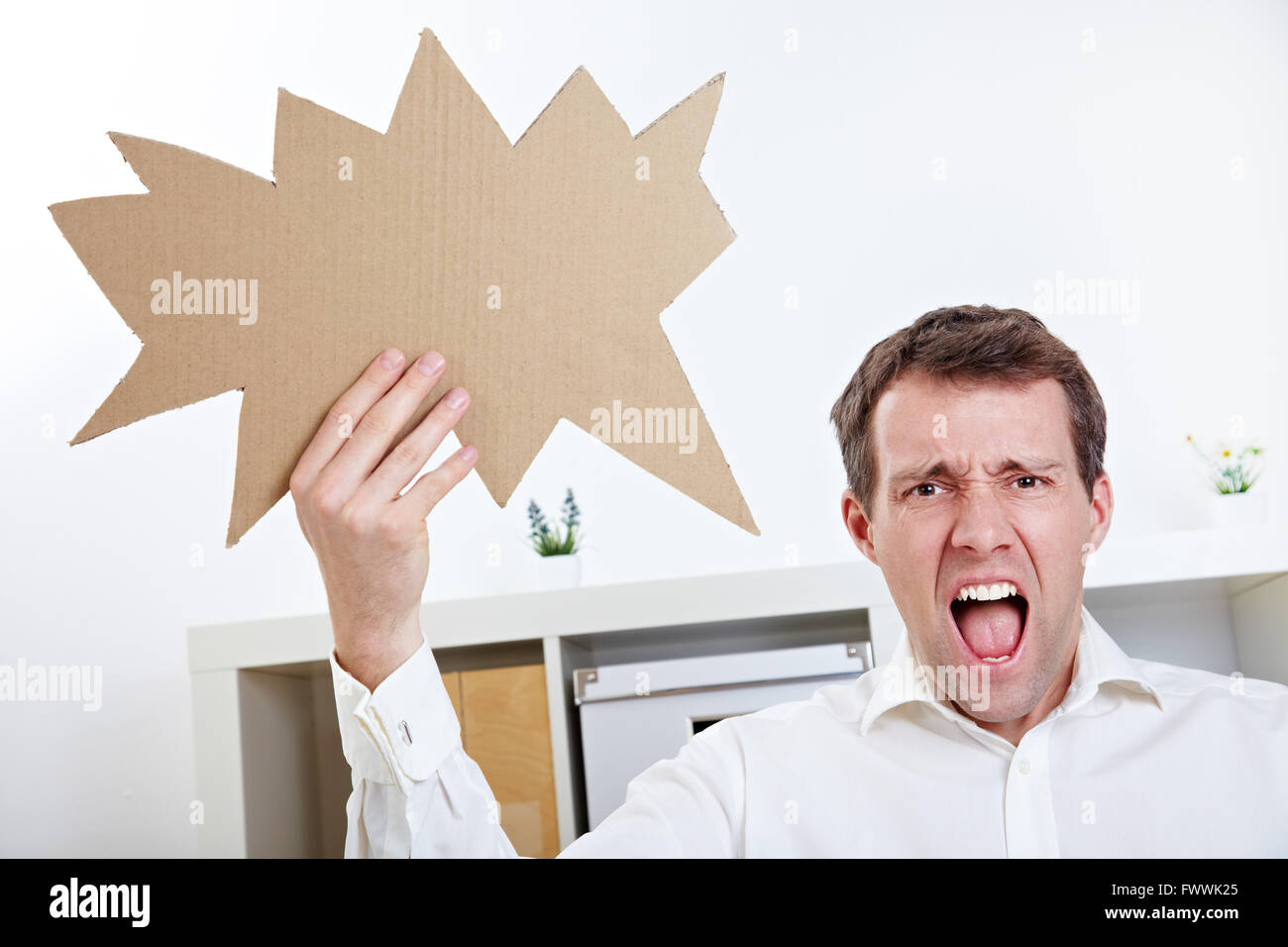 Angry man screaming with speech balloon in his office Stock Photo