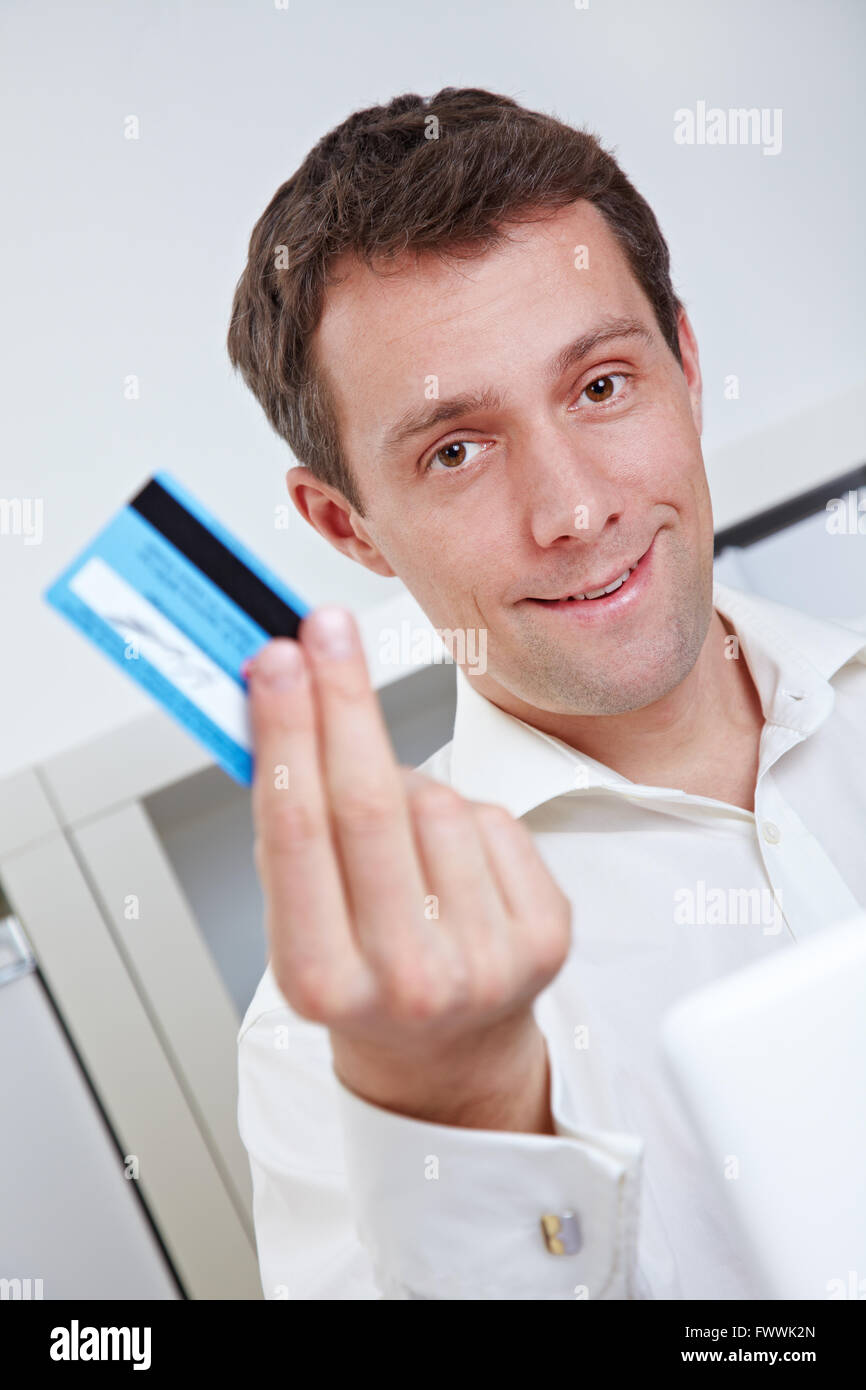 Business man on laptop showing credit card in his office Stock Photo