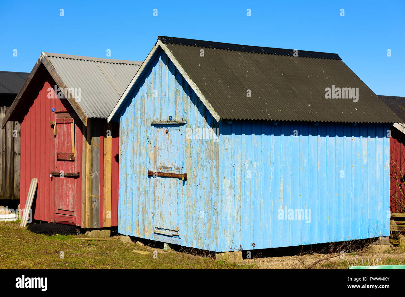 Simrishamn, Sweden - April 1, 2016: Blue and red fishing cabins with metal roofs. These sheds are numbered in the same way that Stock Photo