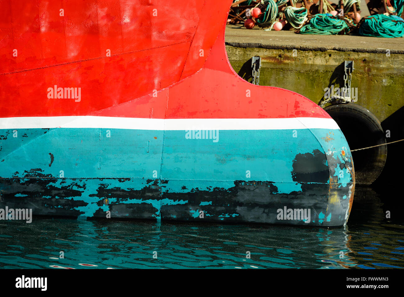 Bulbous bow on the fore of a trawler fishing boat moored at the docks. Red, white and green  are dominating colors. Stock Photo
