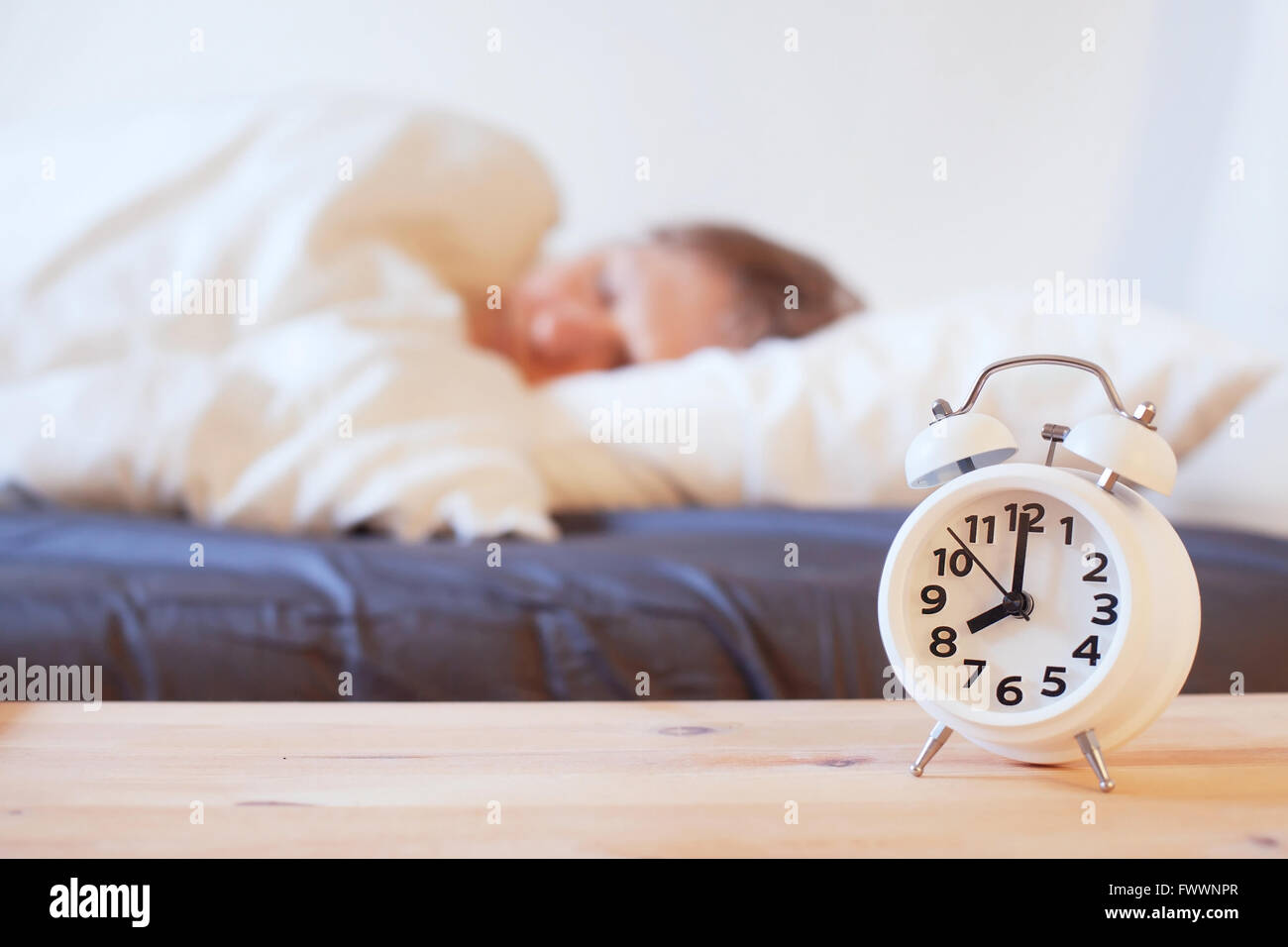 wake up in the morning with alarm clock, person sleeping in the bed Stock Photo