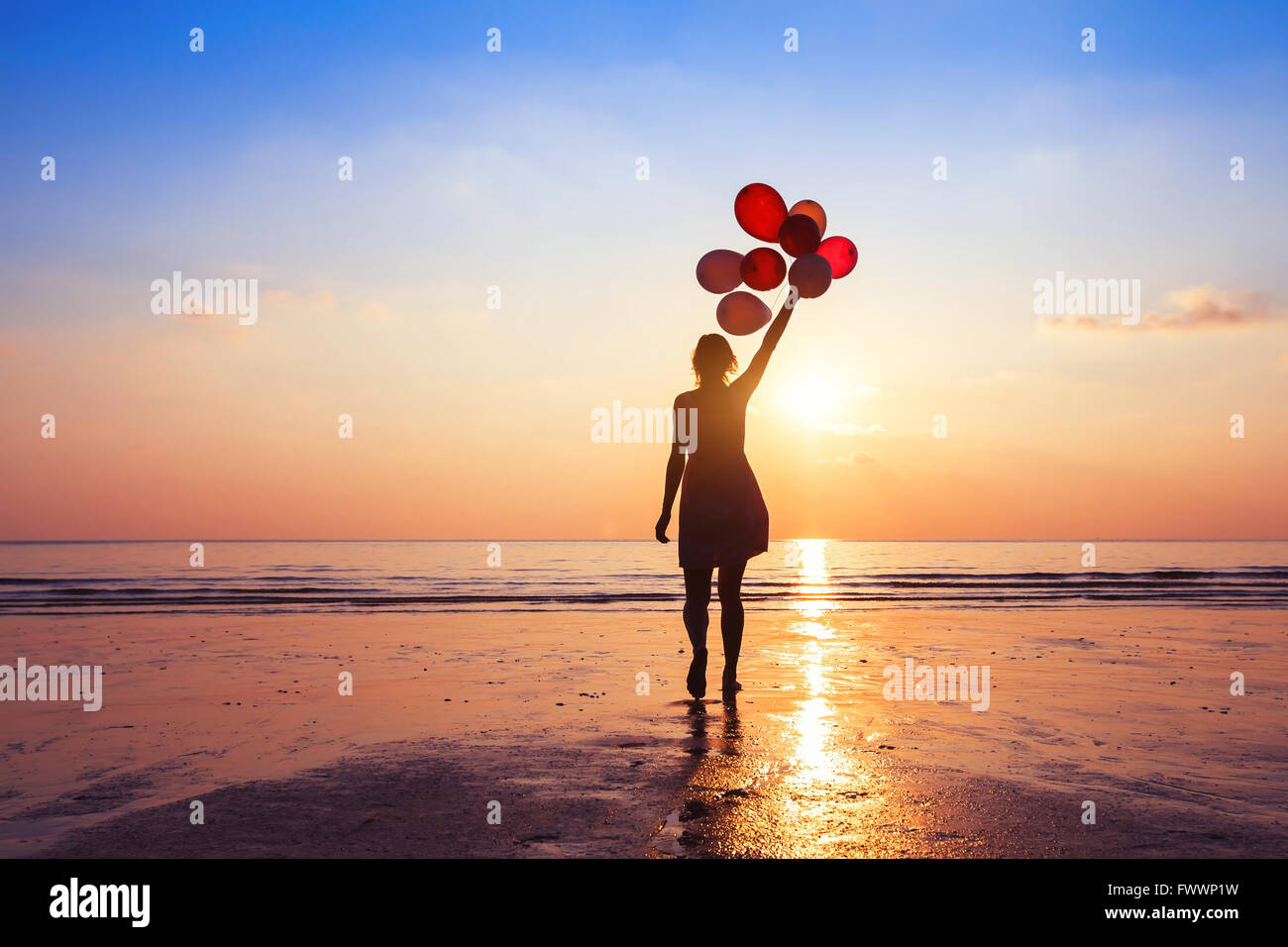 motivation or hope concept, follow your dream and inspiration, girl with balloons at sunset Stock Photo
