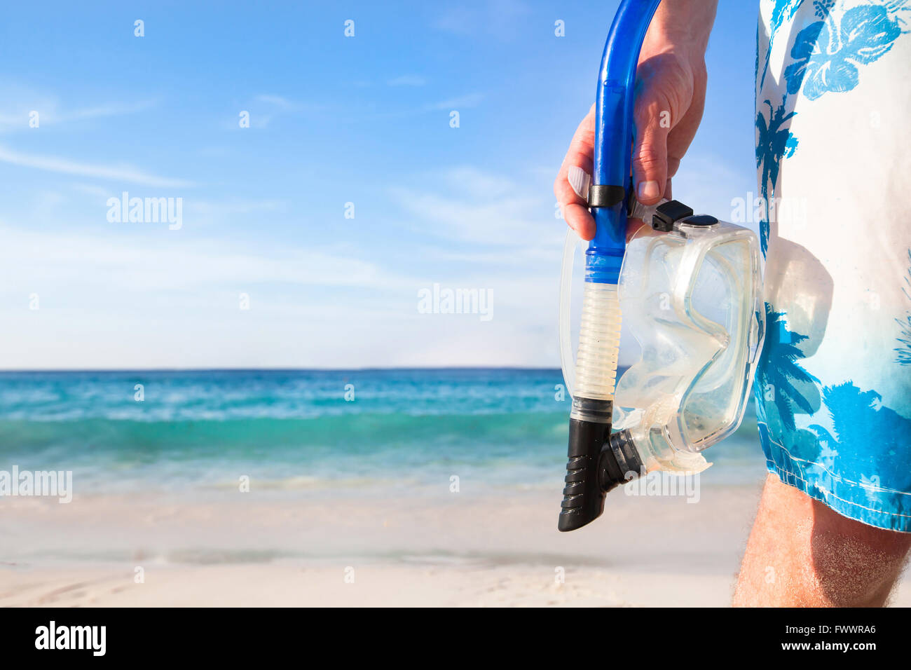 snorkeling background, hand holding mask and snorkel on the beach, active tourism Stock Photo