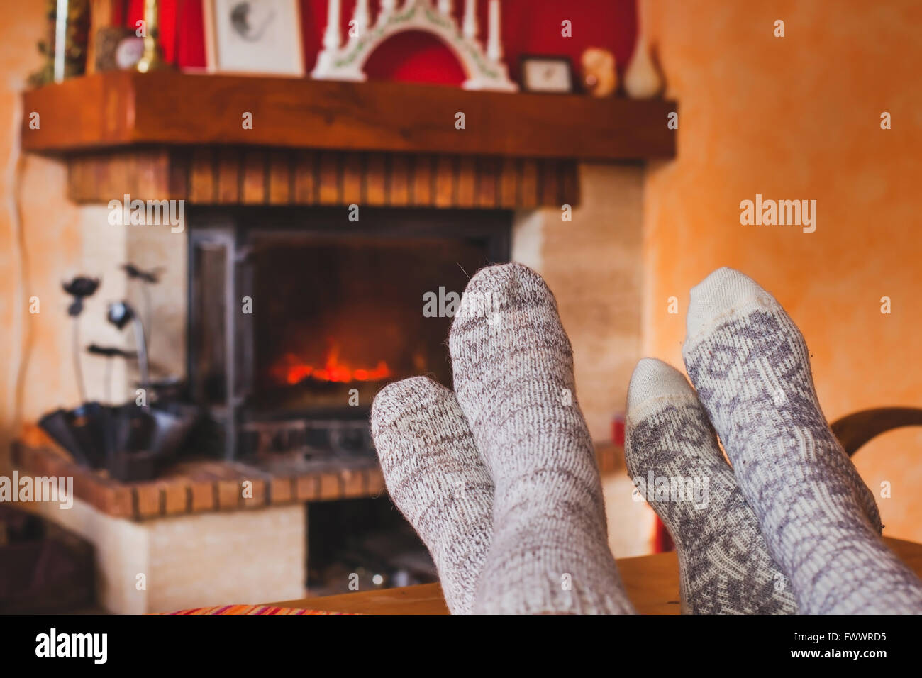feet of couple near cozy fireplace in winter, family at home near fire Stock Photo