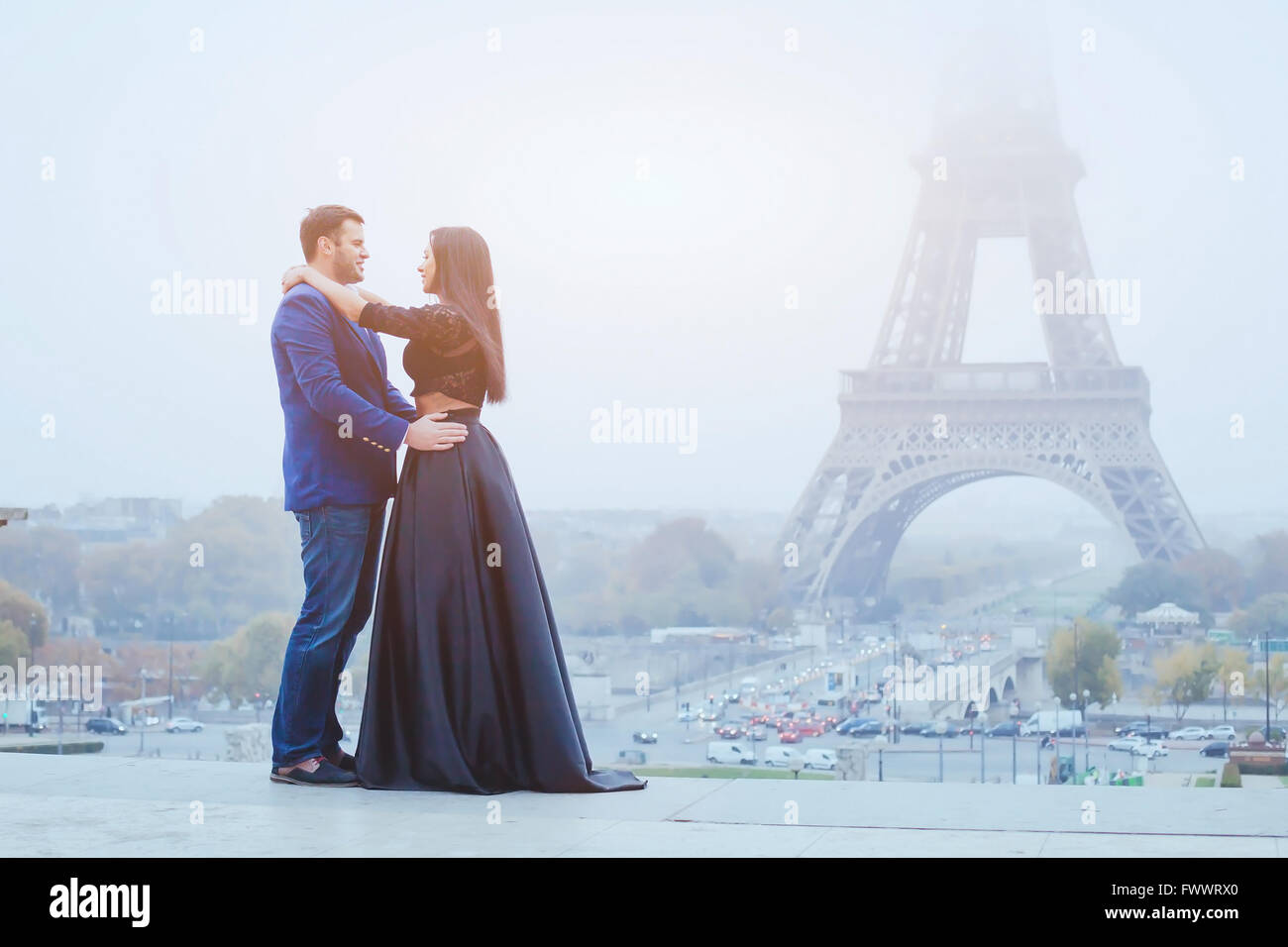 happy couple traveling in Paris, smiling man and woman posing in fancy fashion clothes on Eiffel Tower background during their h Stock Photo
