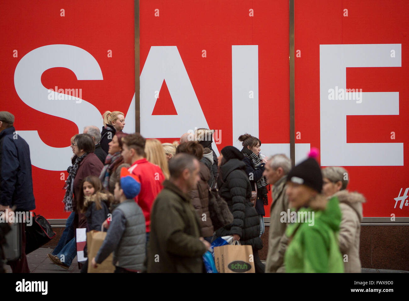A group of shoppers walk under a giant sale sign in Glasgow's Buchanan Street. Stock Photo