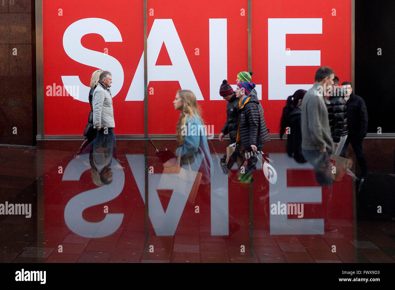 A group of shoppers walk under a giant sale sign in Glasgow's Buchanan Street. Stock Photo