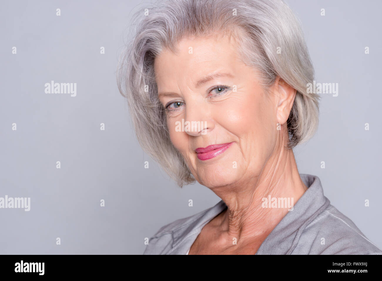 Portrait of a smiling senior woman in front of gray background Stock ...