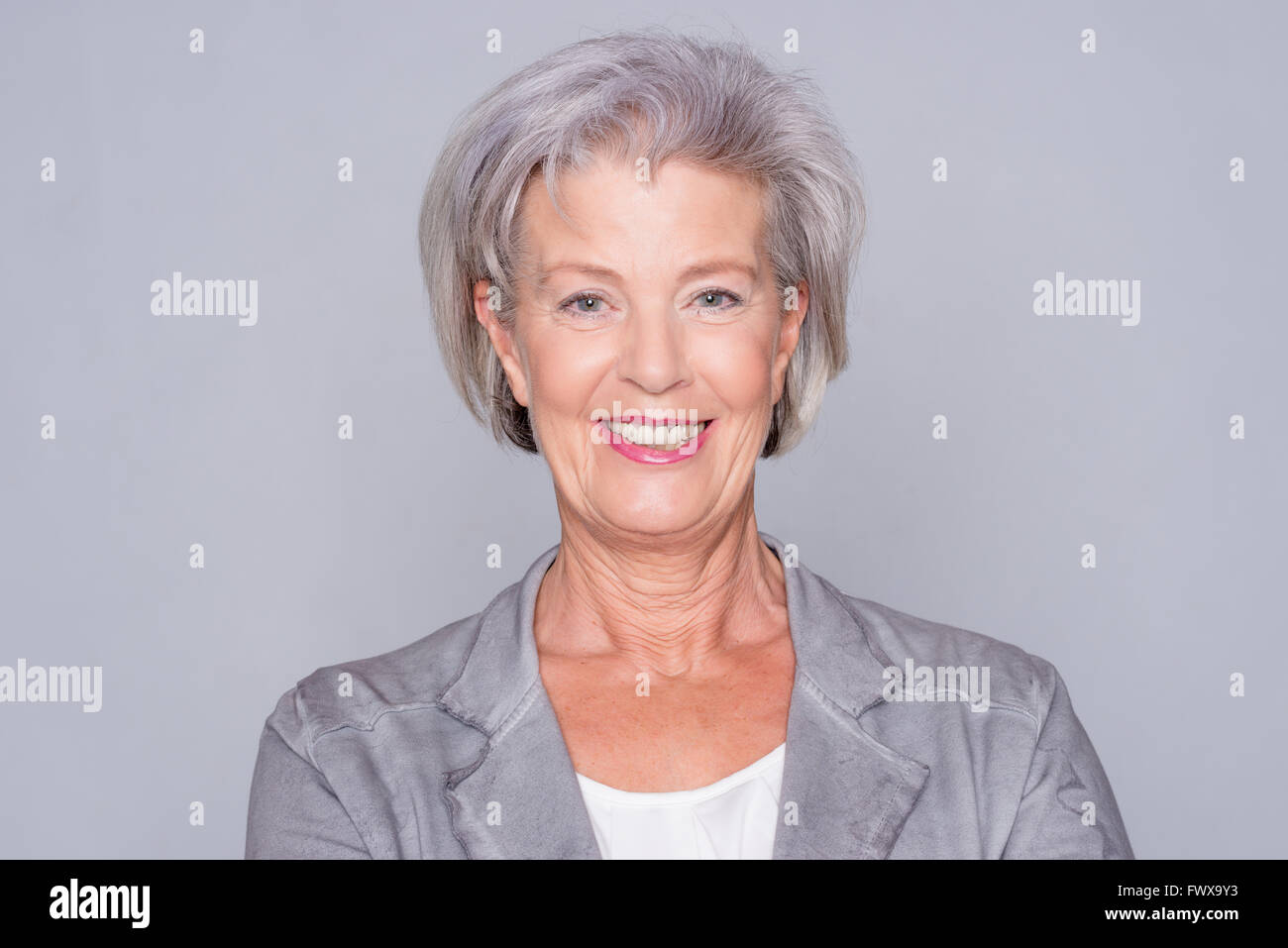Portrait of a smiling senior woman in front of gray background Stock ...