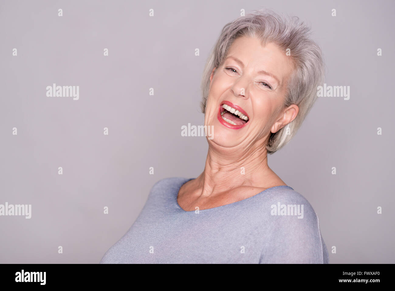 Portrait of a smiling senior woman in front of gray background Stock ...
