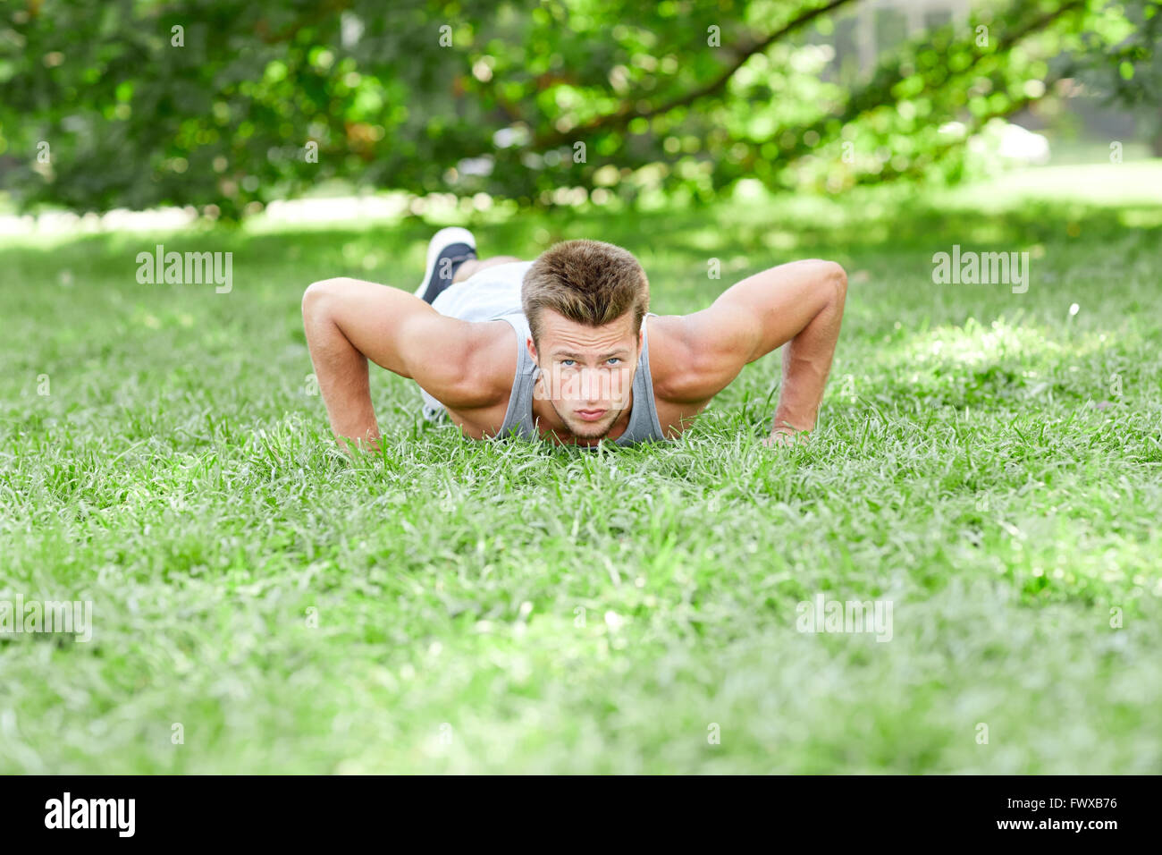 young man doing push ups on grass in summer park Stock Photo - Alamy