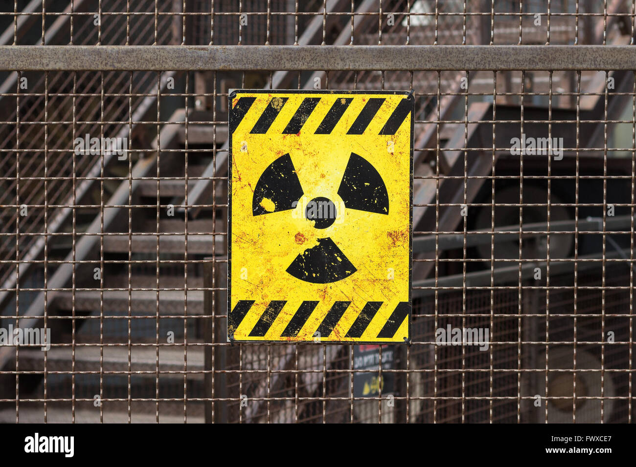 yellow radioactive warning sign on rusty fence Stock Photo