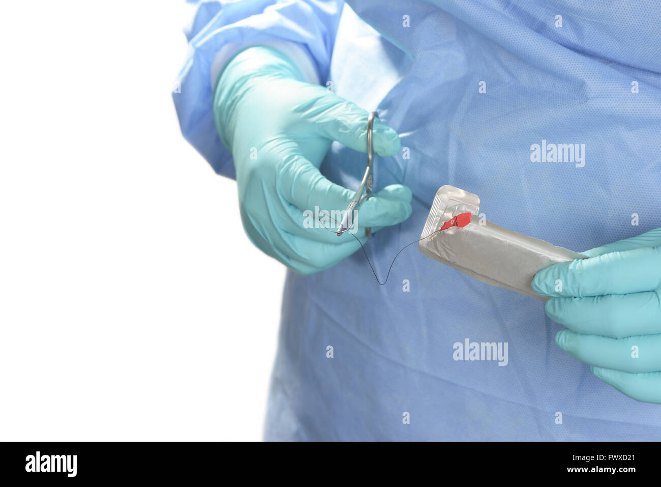 Operating room technician prepares suture for use with needle holder. Stock Photo