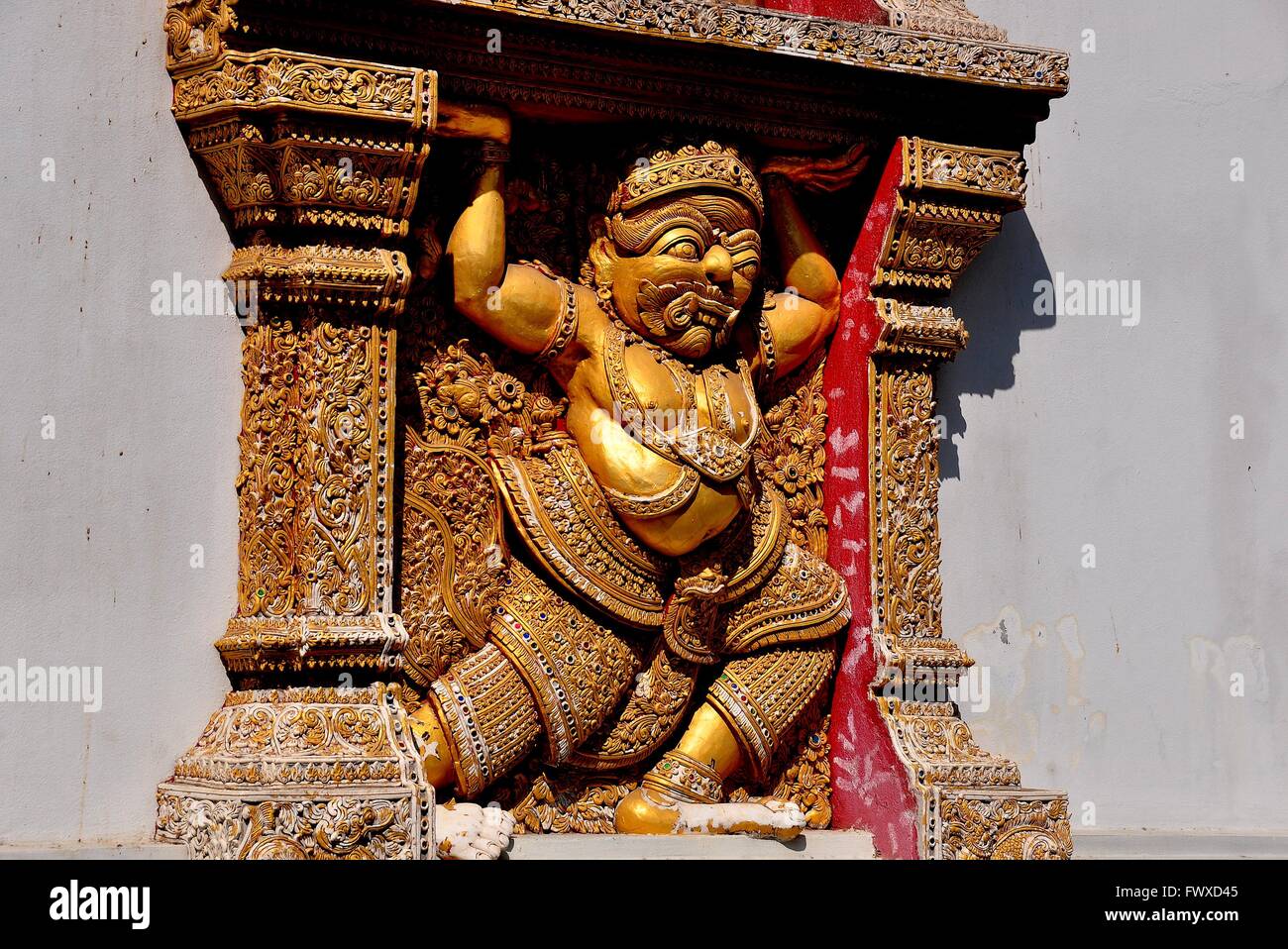 Chiang Mai, Thailand:  Gilded figure of a mythical man holding up a window frame adorns a side wall at Wat Sri Suphan * Stock Photo