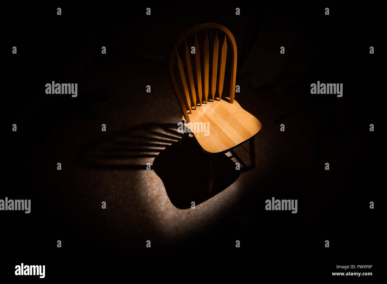 A single wooden chair sits in a spotlight Stock Photo Alamy