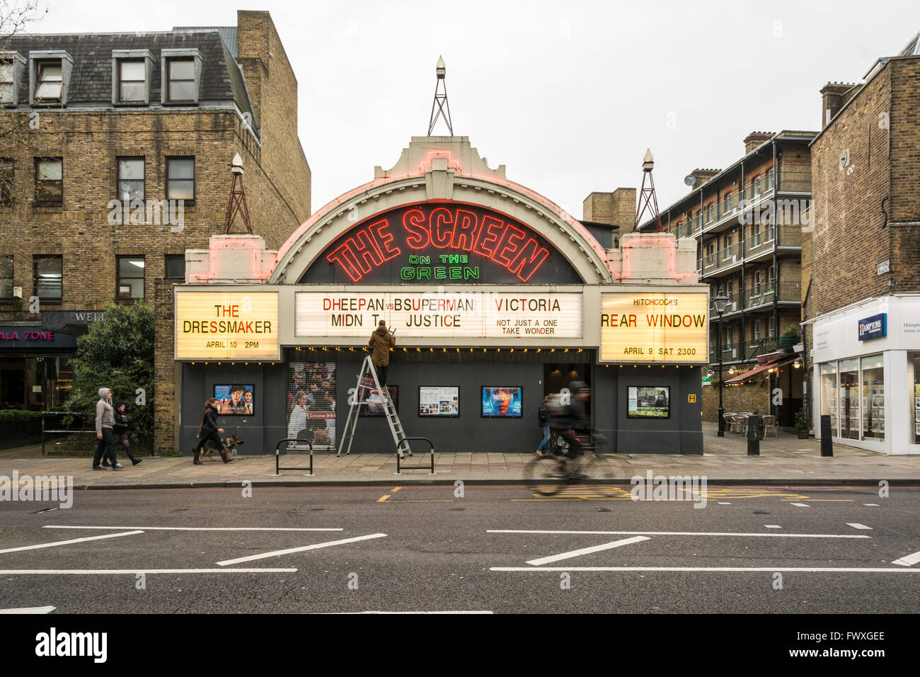 A man up a ladder displays today's listings in front of the Screen on the Green cinema on Upper Street, Islington, London, UK Stock Photo