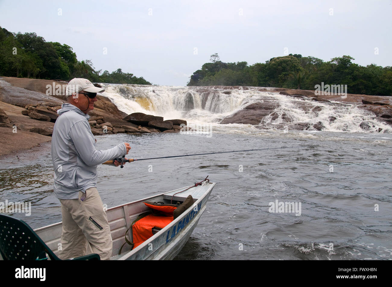 An angler in search of giant payara Dracula fish reels a plug through waterfall rapids on Colombia's Cano Bocon (Inirida River). Stock Photo