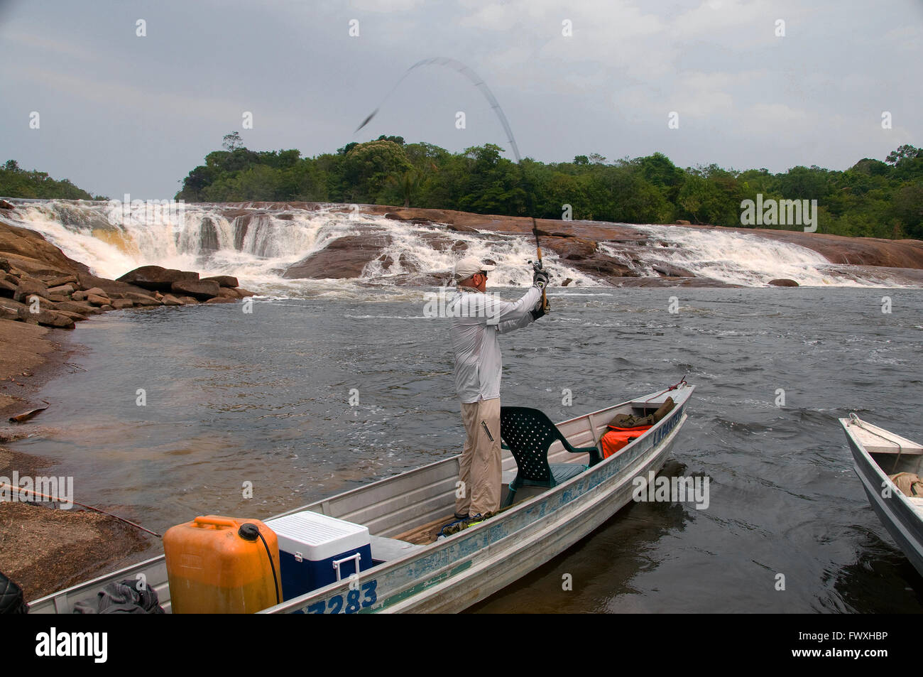 An angler in search of giant payara Dracula fish casts a plug to a waterfall on Colombia's Cano Bocon River on the Llanos. Stock Photo