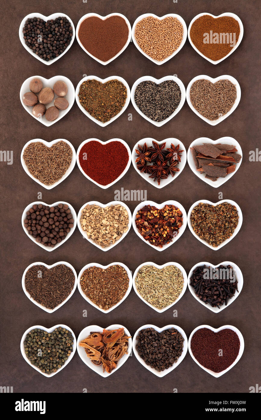 Large spice selection in heart shaped dishes over lokta paper background. Stock Photo