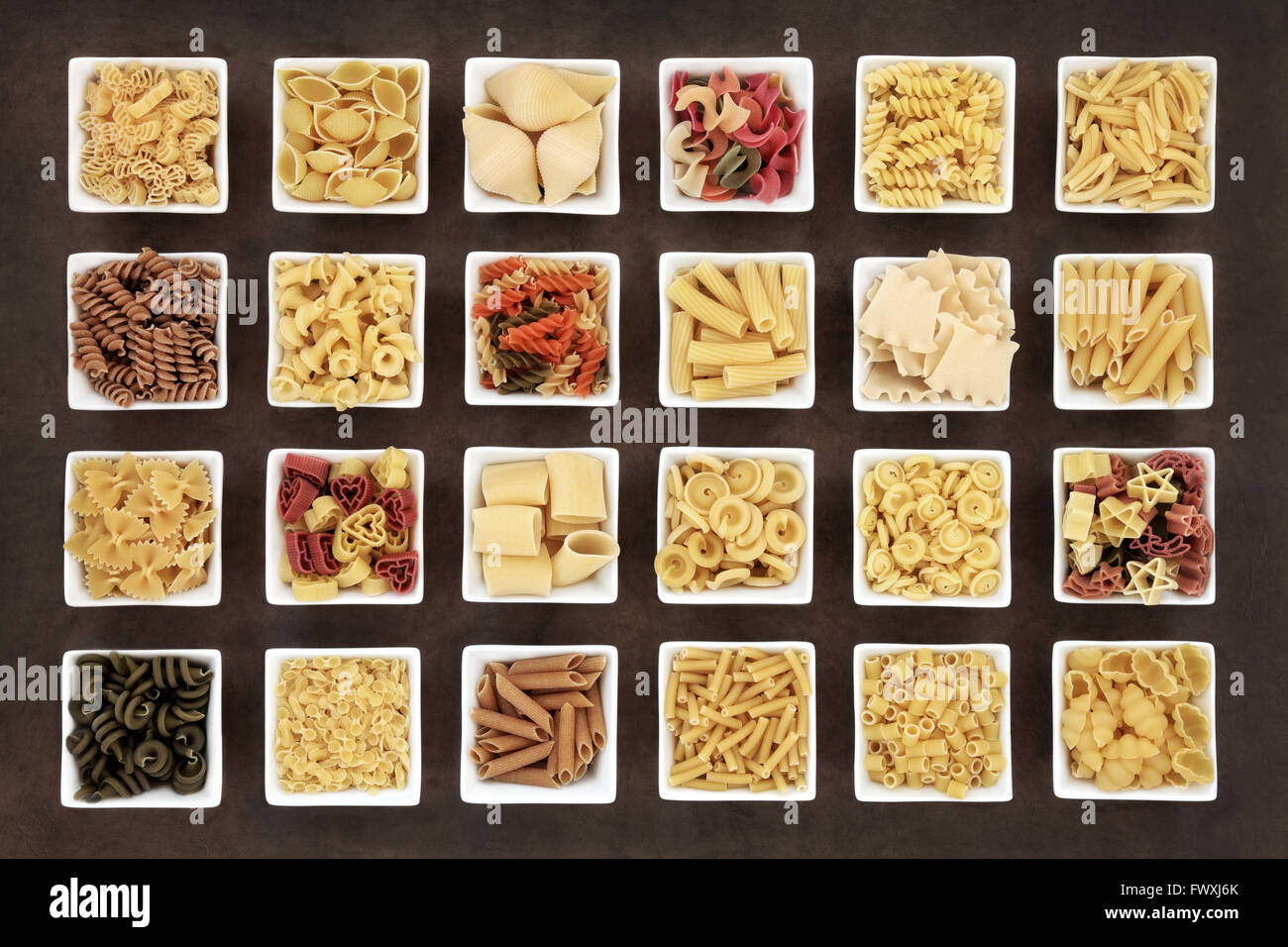 Large italian pasta dried food collection in square bowls over brown lokta paper background. Stock Photo